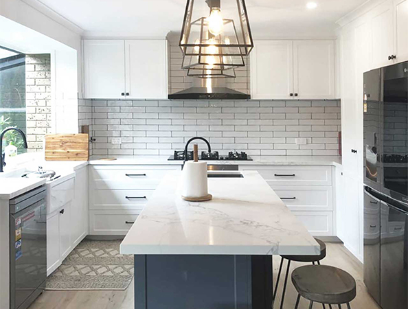 Modern kitchen with white cabinets, marble island, black fixtures, and pendant lighting over the island. Modern kitchen with white cabinets, marble island, black fixtures, and pendant lighting over the island.