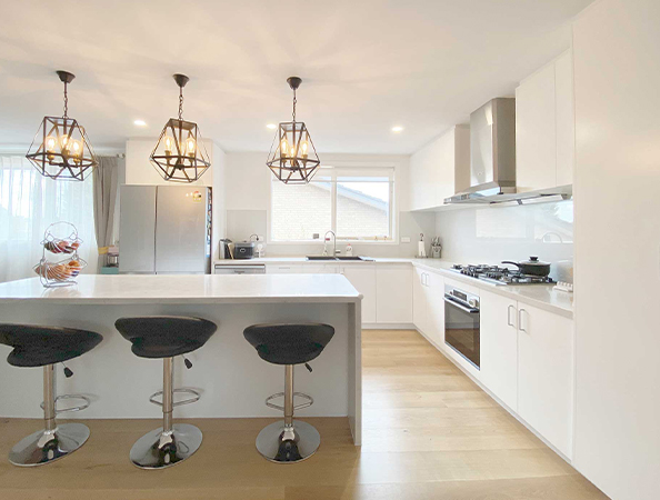 Modern kitchen with white cabinets, island, and three stools. Pendant lights hang above the island. Modern kitchen with white cabinets, island, and three stools. Pendant lights hang above the island.