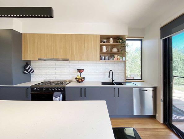 Modern kitchen with black and wood cabinets, white countertops, black appliances, and large window.