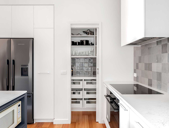 Modern kitchen with stainless steel appliances, a small pantry with shelves, and white cabinetry.