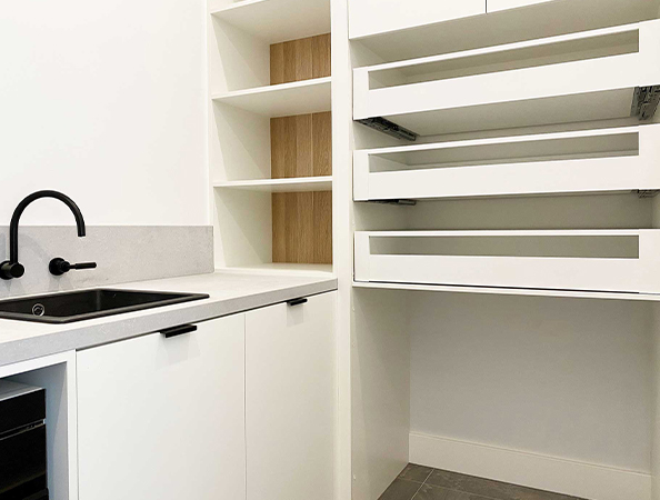 Minimalist kitchen with open shelves, a black faucet, and a countertop. White cabinetry and light wood accents.