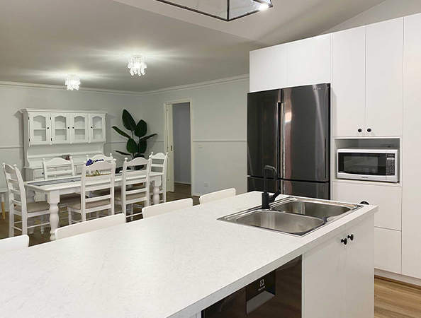 Modern kitchen and dining area with a white island, stainless steel appliances, and a dining table with chairs. Modern kitchen and dining area with a white island, stainless steel appliances, and a dining table with chairs.
