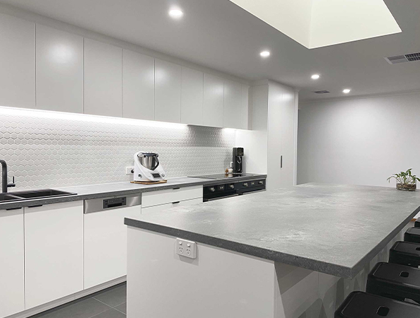 Modern kitchen with white cabinets, a hexagonal tile backsplash, and a large gray island with bar stools.