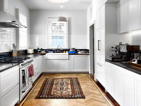 Modern kitchen with white cabinets, a patterned rug, gas stove, and espresso machine on the counter. Modern kitchen with white cabinets, a patterned rug, gas stove, and espresso machine on the counter.
