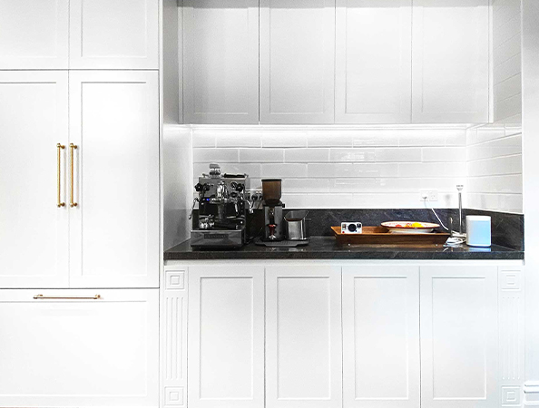 Minimalist white kitchen with espresso machine and kitchenware on a dark countertop. Minimalist white kitchen with espresso machine and kitchenware on a dark countertop.