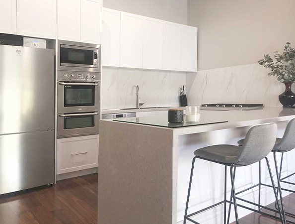 Modern kitchen with marble countertops, stainless steel appliances, and barstools at a central island. Modern kitchen with marble countertops, stainless steel appliances, and barstools at a central island.