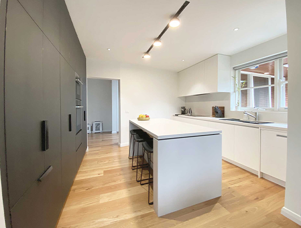 Modern kitchen with black and white cabinetry, an island with stools, wooden floor, and large window. Modern kitchen with black and white cabinetry, an island with stools, wooden floor, and large window.