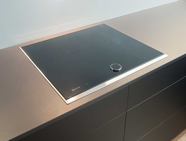 Sleek modern induction cooktop with a single round dial on a minimalist kitchen counter.