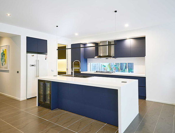 Modern kitchen with navy cabinets, white countertops, a central island, stainless steel appliances, and pendant lights.