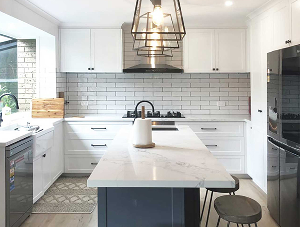 Modern kitchen with white cabinets, subway tile backsplash, marble island, pendant lights, and stainless steel appliances. Modern kitchen with white cabinets, subway tile backsplash, marble island, pendant lights, and stainless steel appliances.