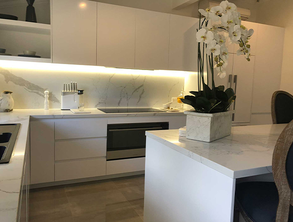 Modern kitchen with white cabinets, marble countertops, and a potted orchid on the island. Modern kitchen with white cabinets, marble countertops, and a potted orchid on the island.