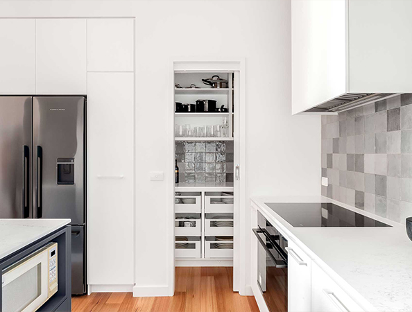 Modern kitchen with stainless steel appliances, white cabinets, and a door leading to a pantry with shelves. Modern kitchen with stainless steel appliances, white cabinets, and a door leading to a pantry with shelves.