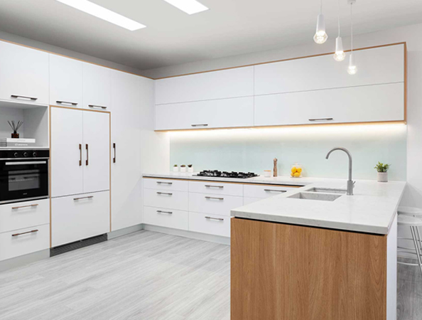 Modern kitchen with white cabinets, built-in oven, cooktop, and wooden island with a sink under hanging lights. Modern kitchen with white cabinets, built-in oven, cooktop, and wooden island with a sink under hanging lights.