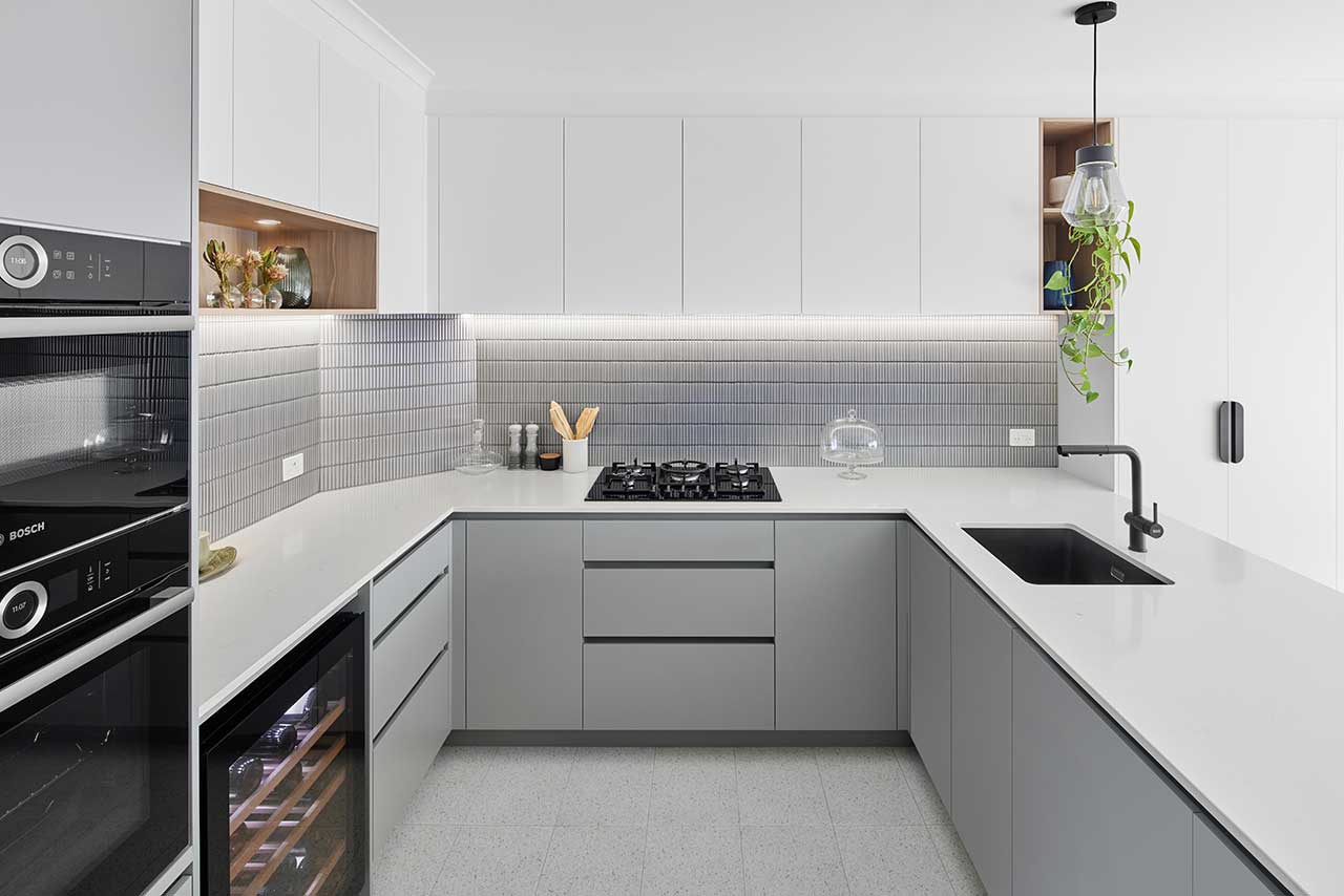 Modern kitchen with white cabinets, U-shaped countertop, gas stovetop, oven, hanging plant, and black faucet. Modern kitchen with white cabinets, U-shaped countertop, gas stovetop, oven, hanging plant, and black faucet.