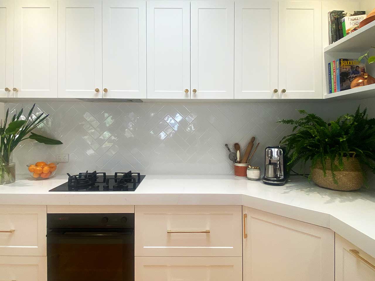 Modern kitchen with white cabinets, herringbone tile backsplash, gas cooktop, and counter appliances. Modern kitchen with white cabinets, herringbone tile backsplash, gas cooktop, and counter appliances.