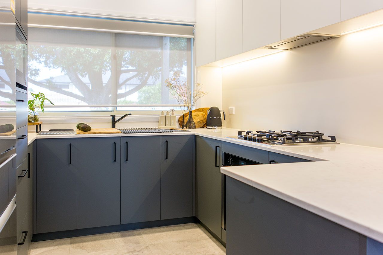 Modern kitchen with grey cabinets, a gas stove, and large window. A potted plant and vase are on the counter. Modern kitchen with grey cabinets, a gas stove, and large window. A potted plant and vase are on the counter.