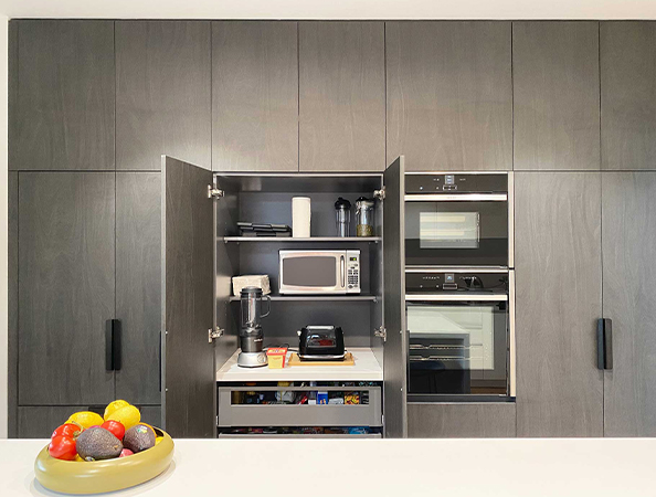 Modern kitchen with open cabinet revealing appliances and fruit bowl on island. Modern kitchen with open cabinet revealing appliances and fruit bowl on island.