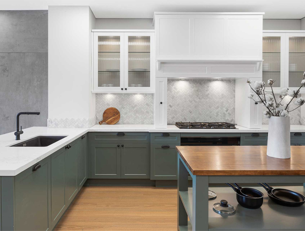 Modern kitchen with green cabinets, white countertops, a wooden island, and a vase of branches on the counter. Modern kitchen with green cabinets, white countertops, a wooden island, and a vase of branches on the counter.