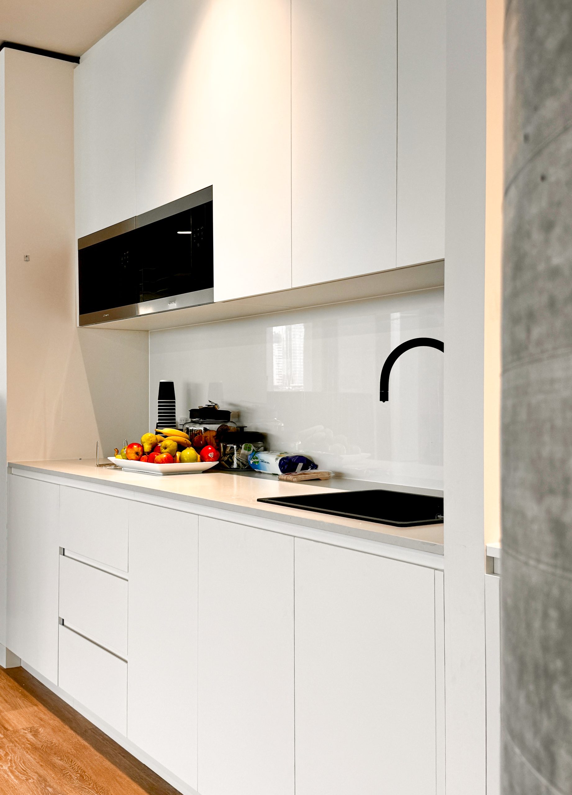 Modern kitchen with white cabinets, a black faucet, and a countertop with assorted fruits and kitchen items. Modern kitchen with white cabinets, a black faucet, and a countertop with assorted fruits and kitchen items.